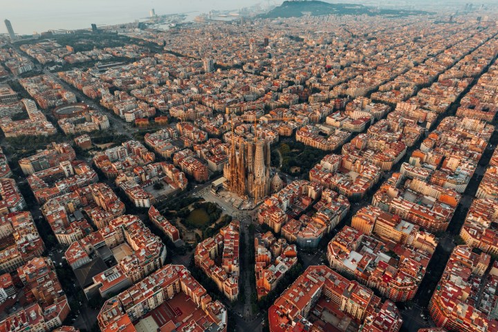 Aerial view of a city with a large cathedral in the center surrounded by dense grid-patterned buildings.